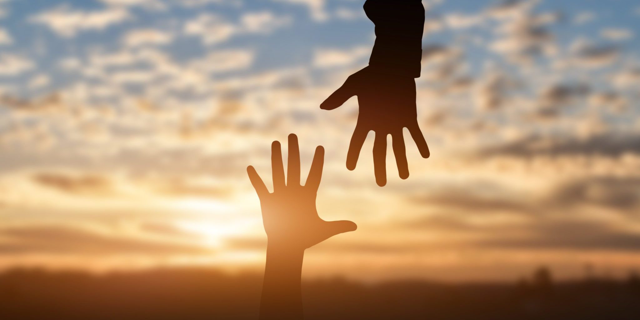 Silhouette of reaching, giving a helping hand, hope and support each other over sunset background. Help concept